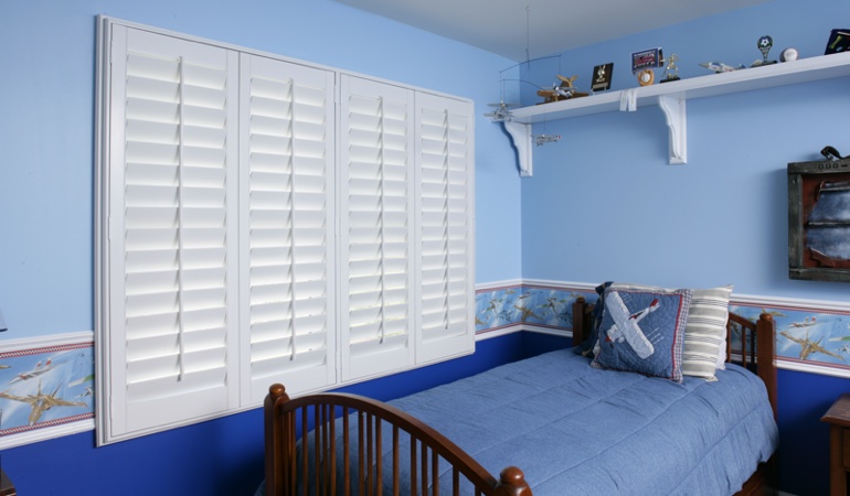Large plantation shutters covering window in blue kids bedroom in Southern California 